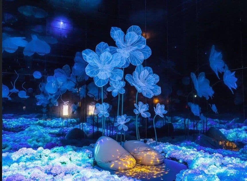 Visitors' cushions in a field of glowing flowers beneath translucent blossom sculptures — Raindrop Garden, The Healing Garden of Gods